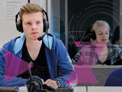 Ein junger Dolmetscher während einer Simultanübersetzung Ein junger Dolmetscher im blauen Kapuzenpulli sitzt an einem Tisch. Er trägt ein Headset und wirkt konzentriert. Vor ihm auf dem Tisch liegt eine Tastatur und ein weiteres Headset. Hinter ihm in der Kabine sitzt eine junge Dolmetscherin, ebenfalls mit Headset, die gerade spricht. Das Bild wird von magentafarbenen Dreiecken überlagert, die für den Ausbildungsgang Übersetzer*in/Dolmetscher*in an der WDS stehen.